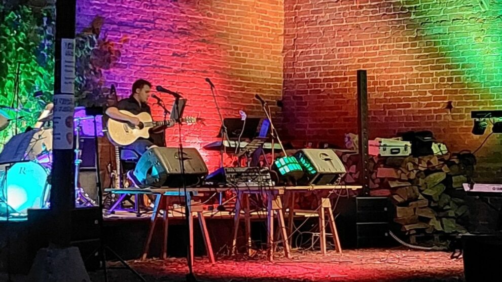 A guitarist playing under coloured lights.